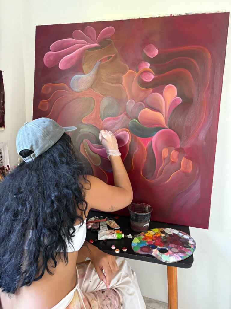 Zoe with her back turned to the camera painting on a canvas.