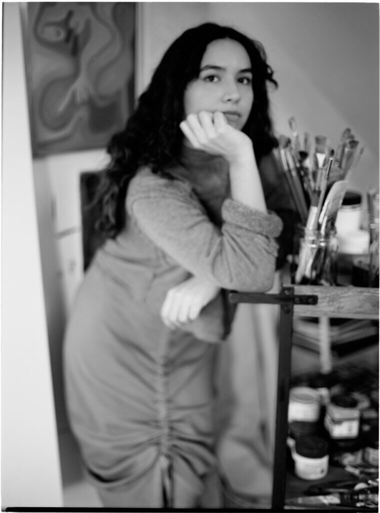 Image of Zoe Dejesus next to a painting cart full of brushes.
